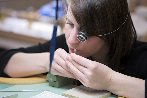 Eine junge Uhrmacherin von Audemars Piguet prüft ihre Arbeit an einem winzigen Werkteil