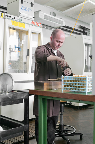 A watchmaker preparing a set of plates for industrial machining
